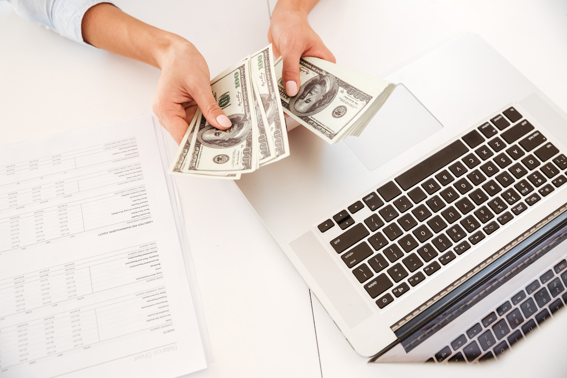 Cropped Image of Businesswoman Holding Money near Laptop